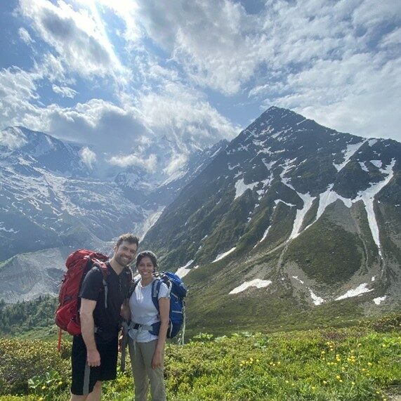 Two people standing underneath an mountain